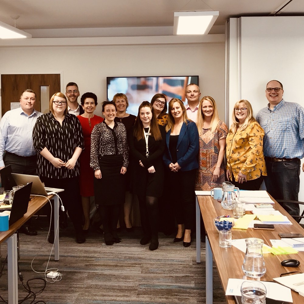 A group of course delegates standing together in a training room